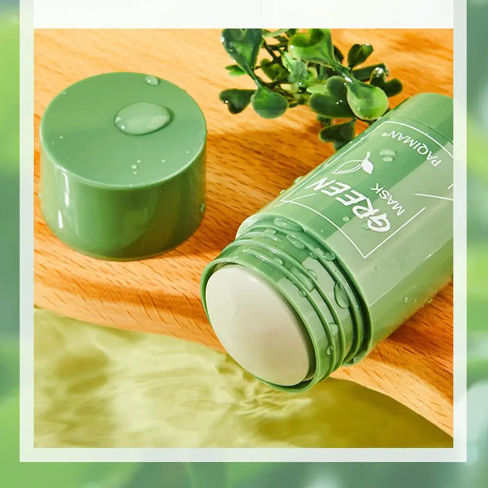 Green skincare mask jar and container on a wooden surface with a plant in the background